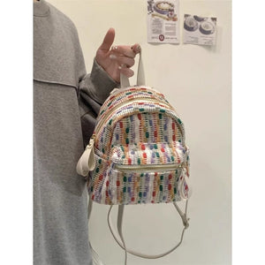 Colorful striped backpack held by a person against a plain background