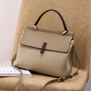 Beige tote bag with a black handle and strap on a beige surface