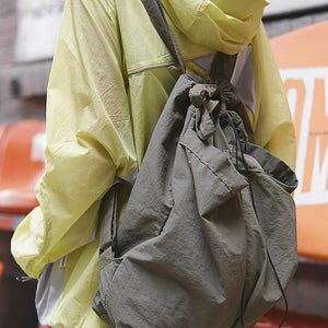 Person wearing a yellow raincoat with a large capacity nylon backpack purse in an urban setting