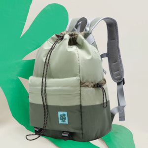 Green and gray backpack with a drawstring on a green and beige background