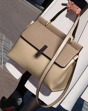 Beige tote bag with a strap held by a person in an urban setting