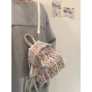 Person wearing a rainbow knit backpack with a plain background