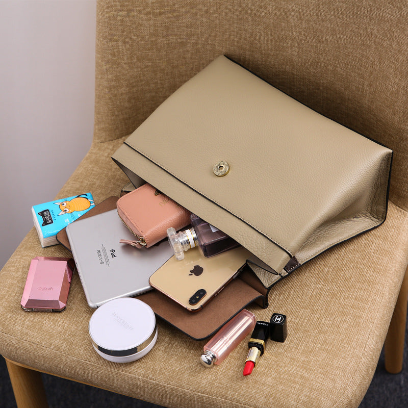 Beige clutch bag filled with various items on a chair