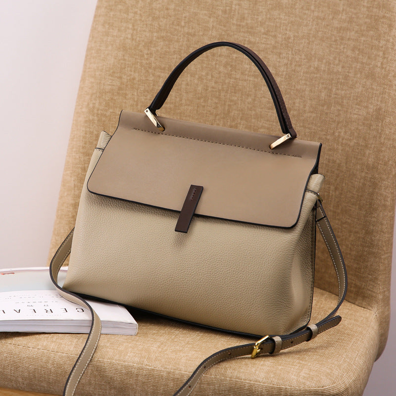 Beige tote bag with a black handle and strap on a beige surface