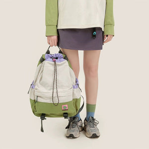 Person holding a green and beige backpack with a plain background