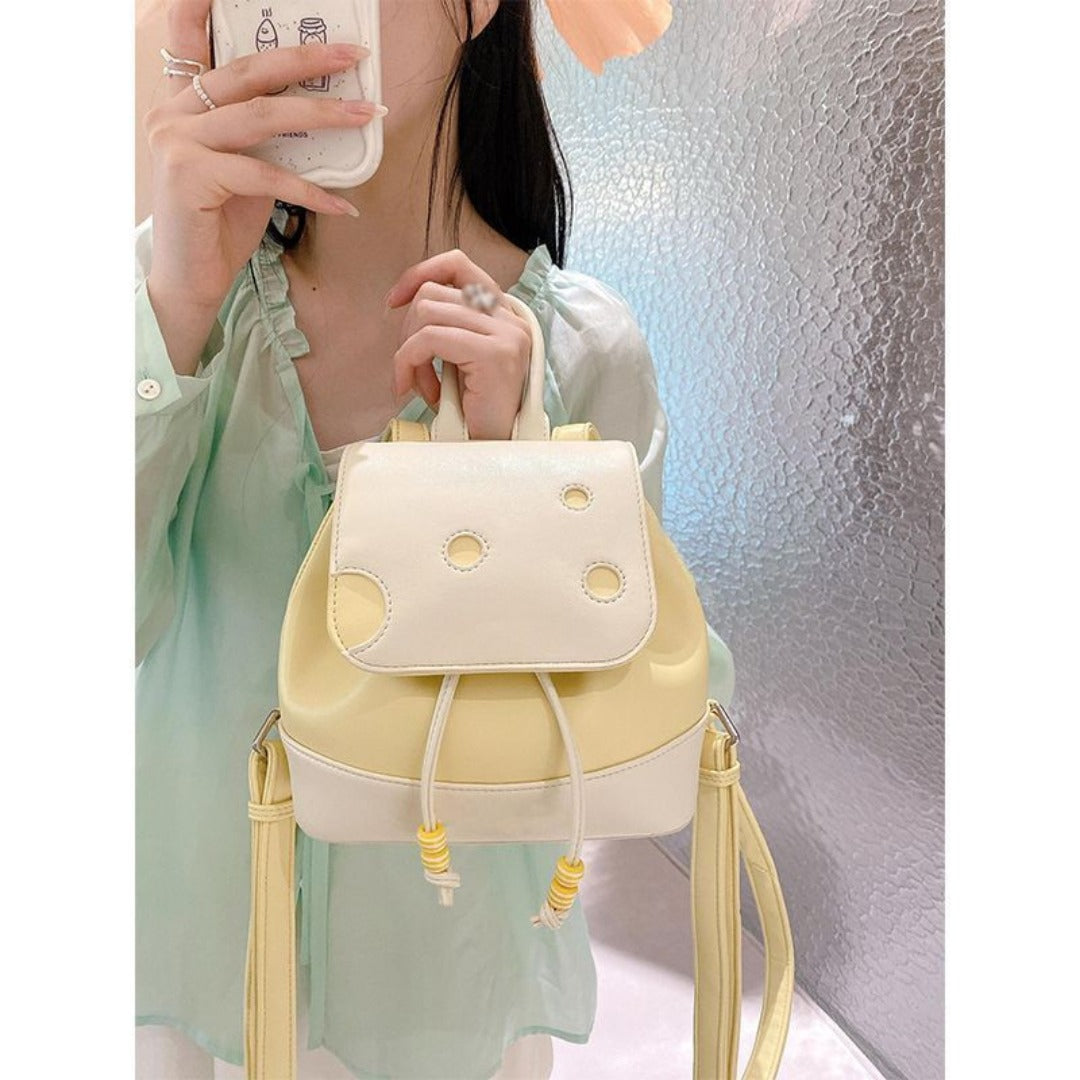 Person holding a cute cheese mini backpack with a textured wall background