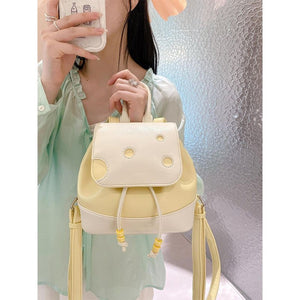 Person holding a cute cheese mini backpack with a textured wall background