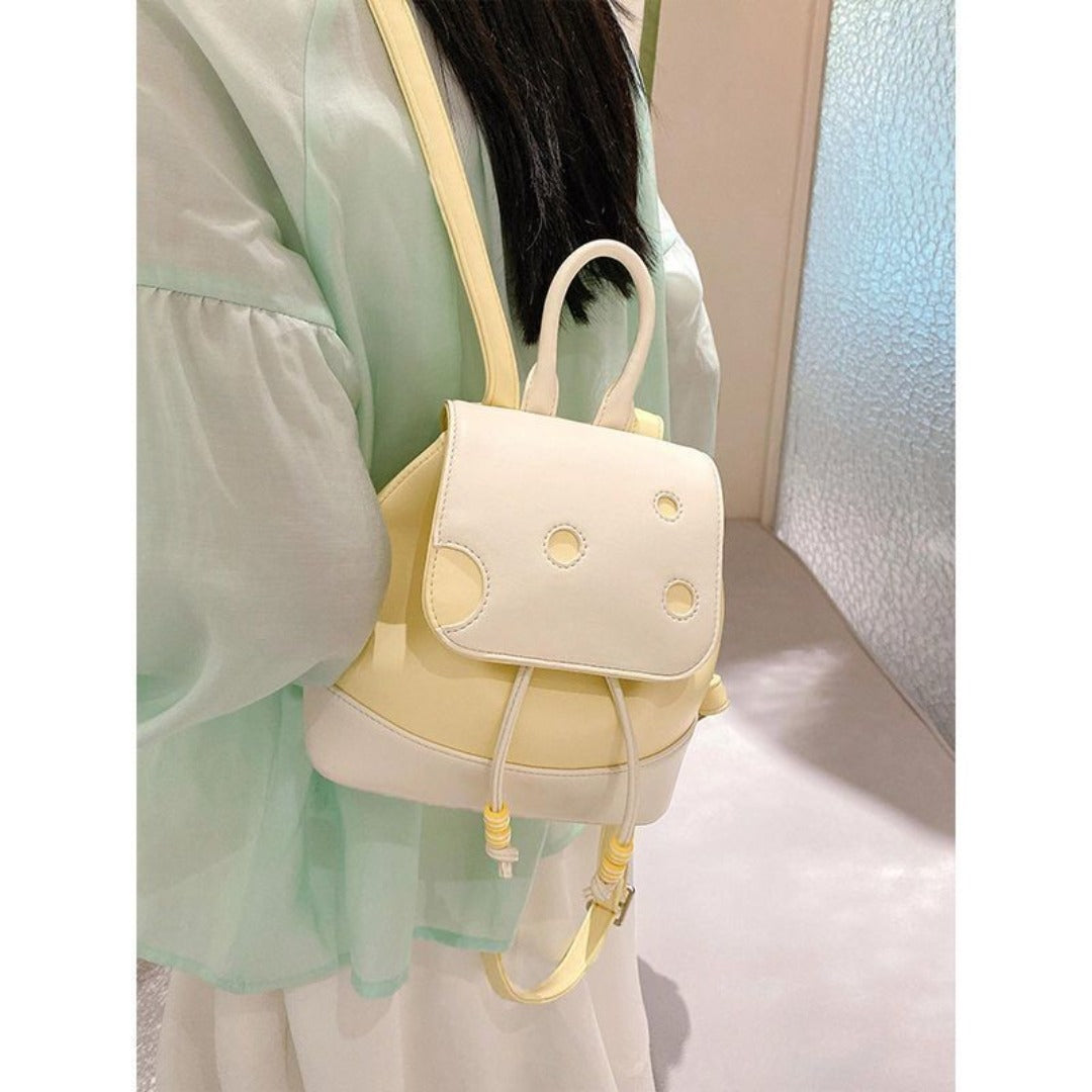 Person wearing a light green outfit with a cute cheese mini backpack.