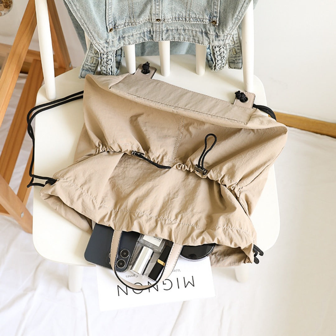 Beige bag with a phone and wallet on a white chair