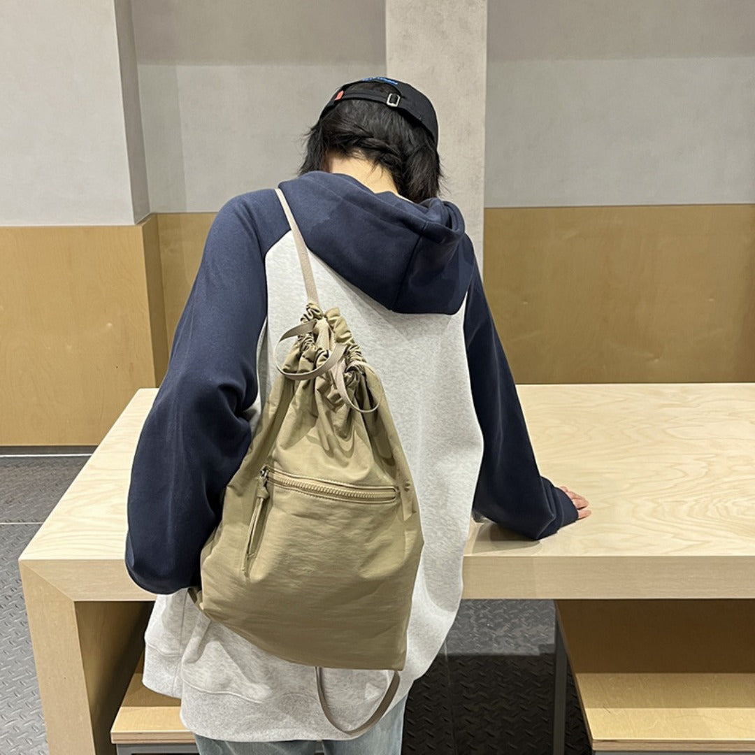 Person wearing a beige backpack sitting on a bench indoors