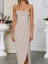 Woman wearing a beige side slit halter maxi dress in an elegant indoor setting with floral arrangements.