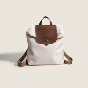 nylon commuter backpack purse with brown leather flap and straps on a light background