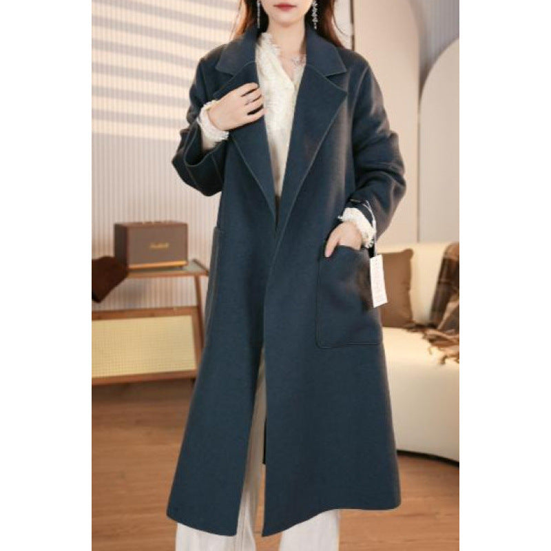 Person wearing a long dark blue coat in an indoor setting