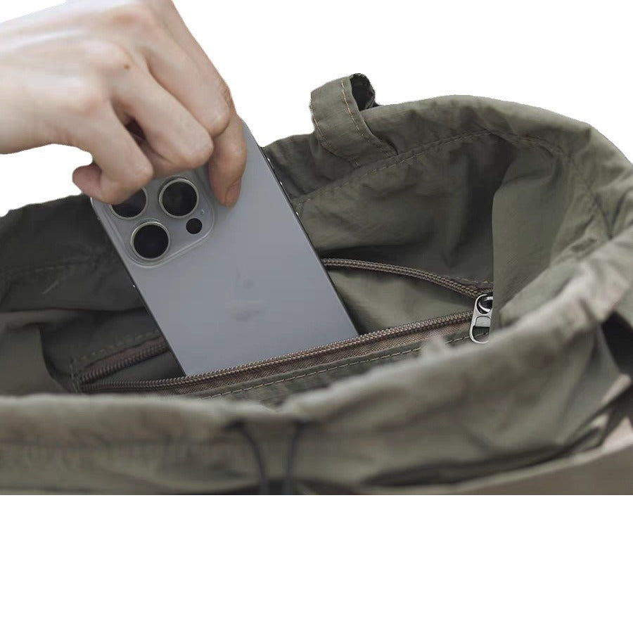 Person placing a smartphone into a green backpack