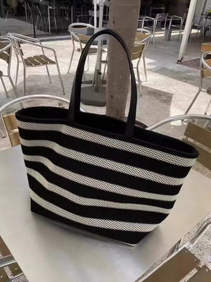 Black and white striped tote bag on a table with outdoor furniture in the background