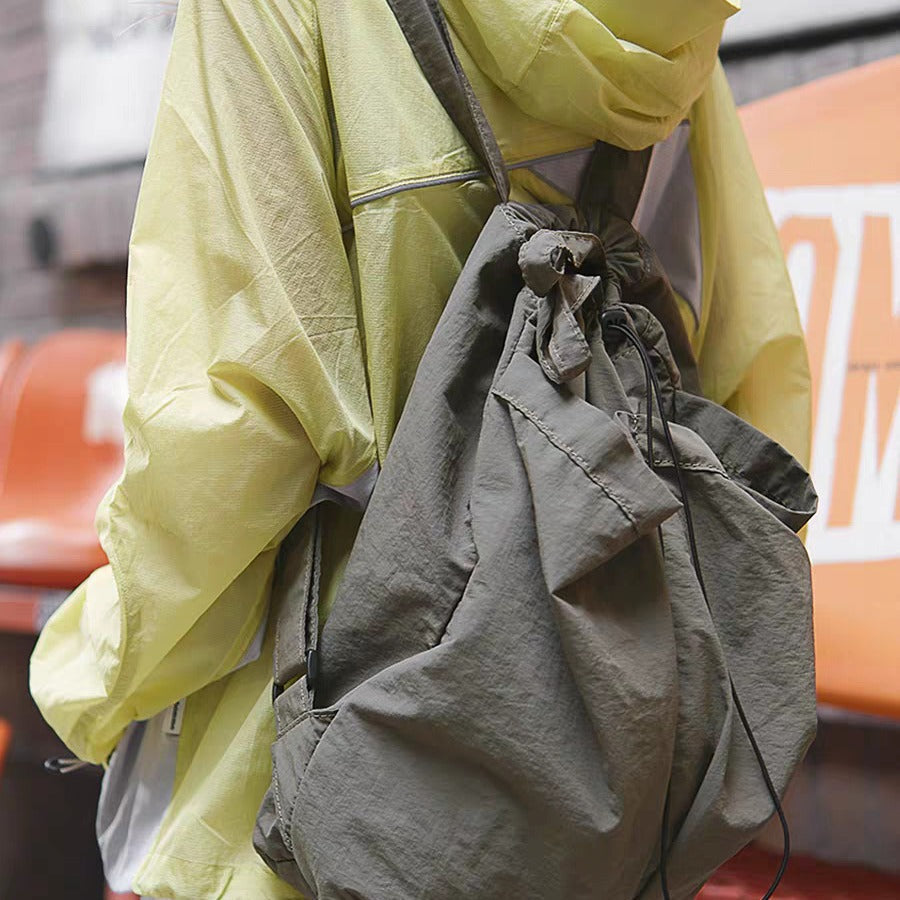 Person wearing a yellow raincoat with a large capacity nylon backpack purse in an urban setting