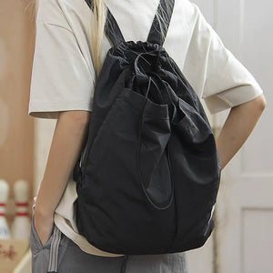 Person wearing a black drawstring bag with a neutral background