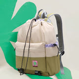Two backpacks, one beige and one green, with a visible brand logo on a green and white background.
