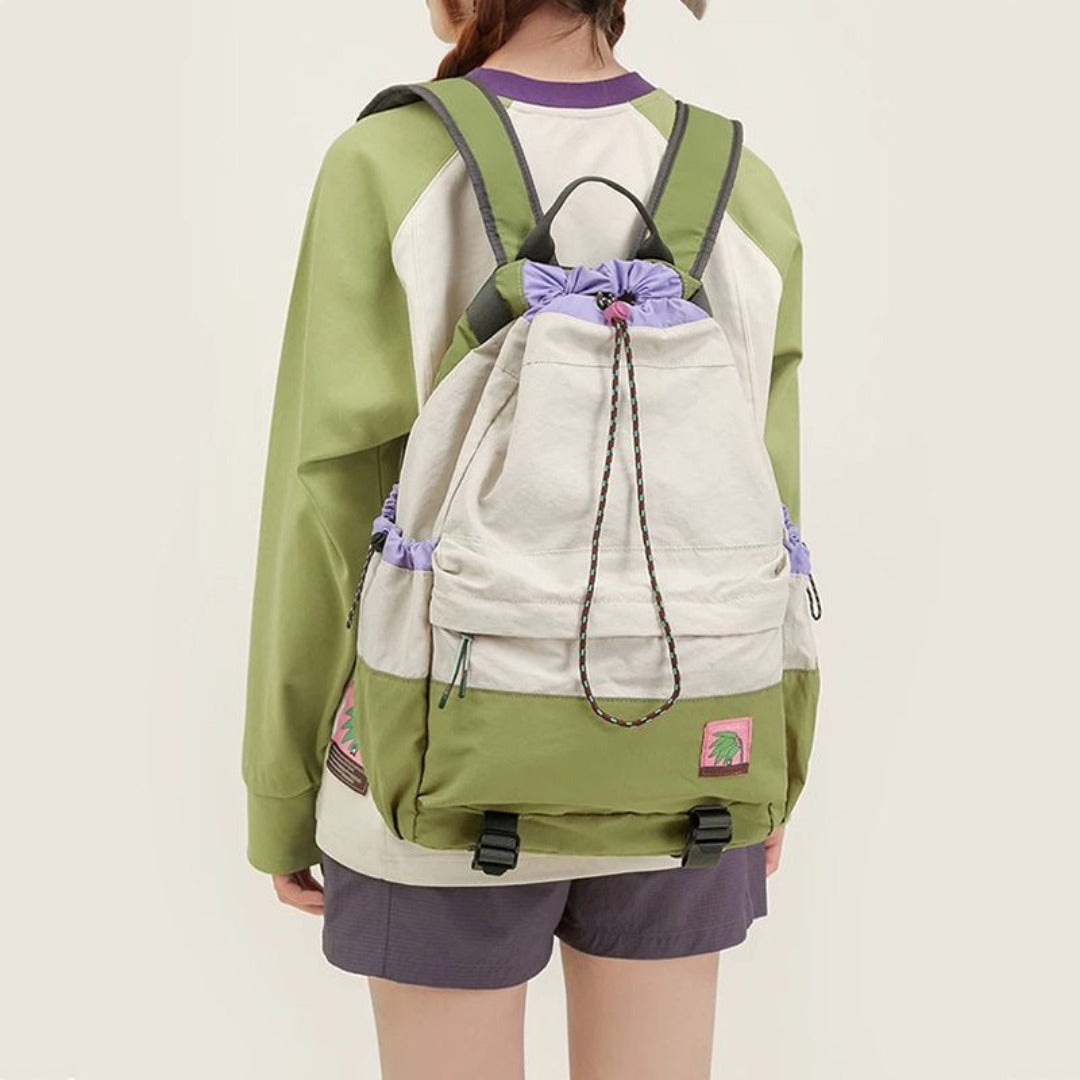 Person wearing a green and beige drawstring bag on a plain background