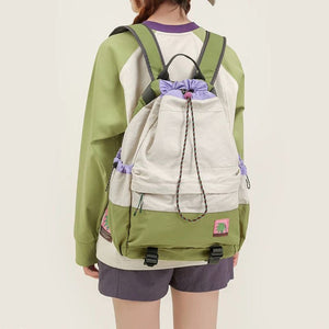 Person wearing a green and beige drawstring bag on a plain background
