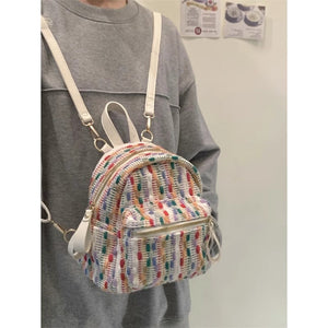 Person wearing a colorful striped backpack with a plain background