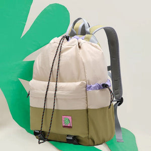 Two backpacks, one beige and one green, with a visible brand logo on a green and white background.