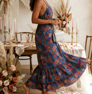 Woman in a floral dress standing in a decorated room with candles and flowers.