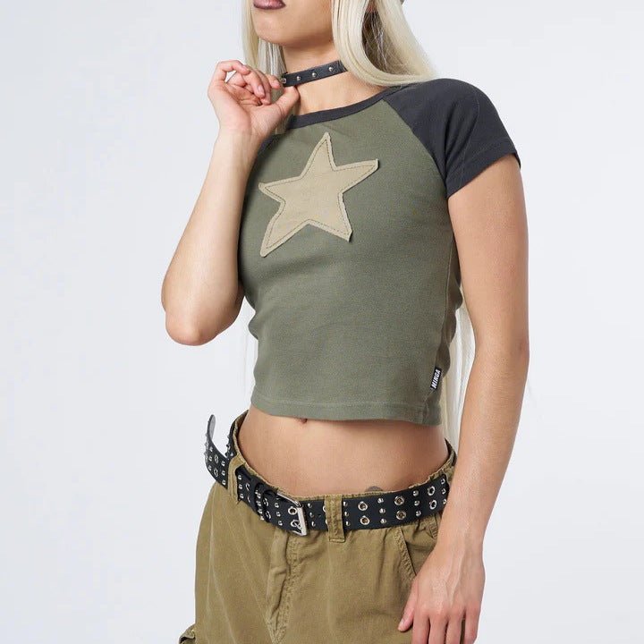 Person wearing a green Y2K cropped t-shirt with a star design and beige pants on a white background