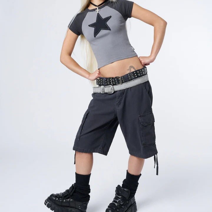 Person wearing a gray crop top with a star design and black cargo shorts on a white background